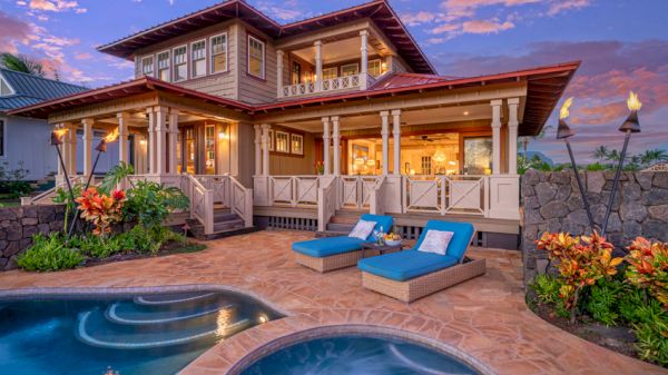 The image shows a luxurious house with a pool and patio, featuring two lounge chairs, greenery, and tiki torches, all under a colorful evening sky.