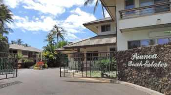 The image shows the entrance of "Piumoa Beach Estates," a residential area with gated entry, tropical plants, and a clear sky with a few clouds.